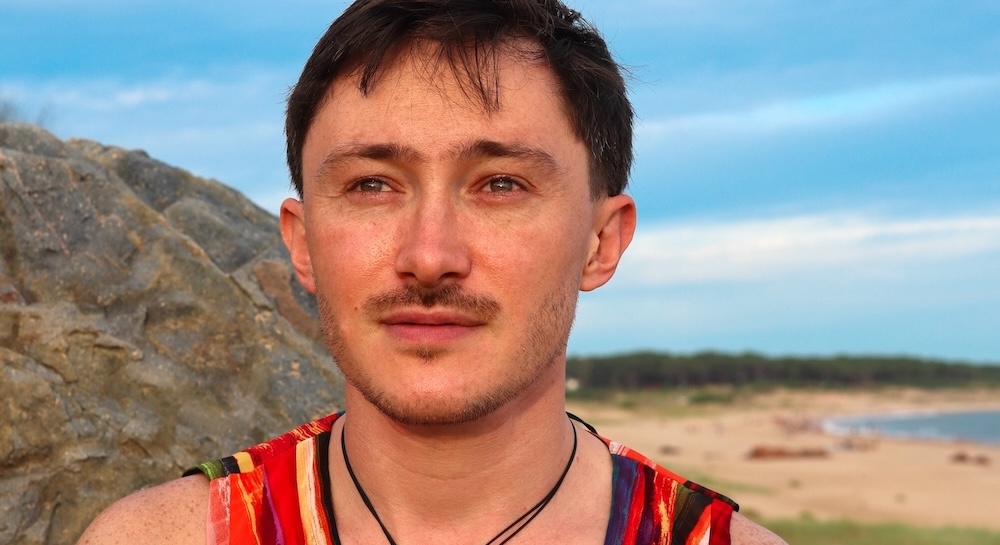 Alex Etchart, British-Uruguayan musician and creator of Vientos, standing against a backdrop of Uruguayan sand dunes and the Atlantic ocean